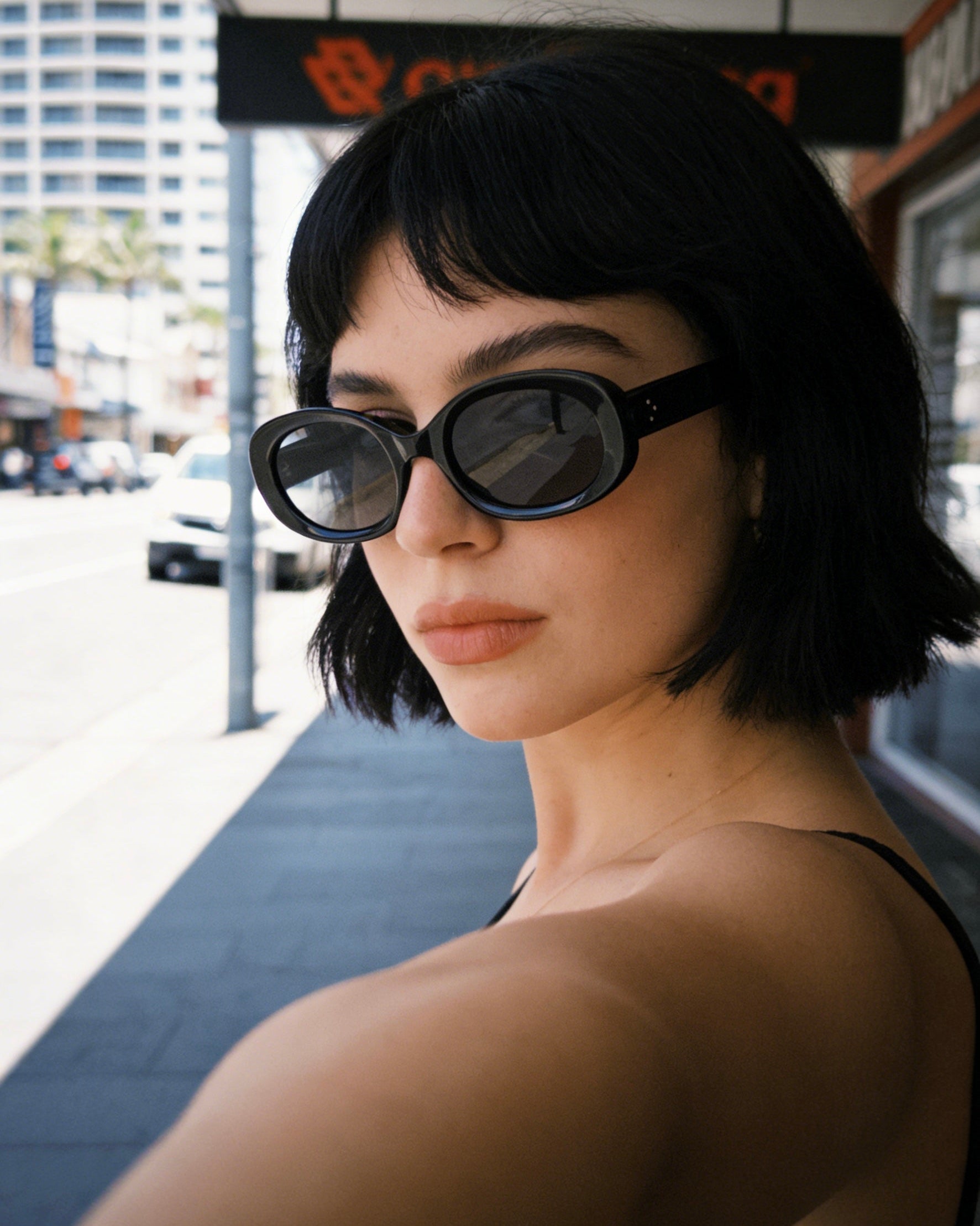 Minimalist black bold oval sunglasses featuring dark polarized lenses and 100% UV protection, aesthetic chic fashion eyewear.