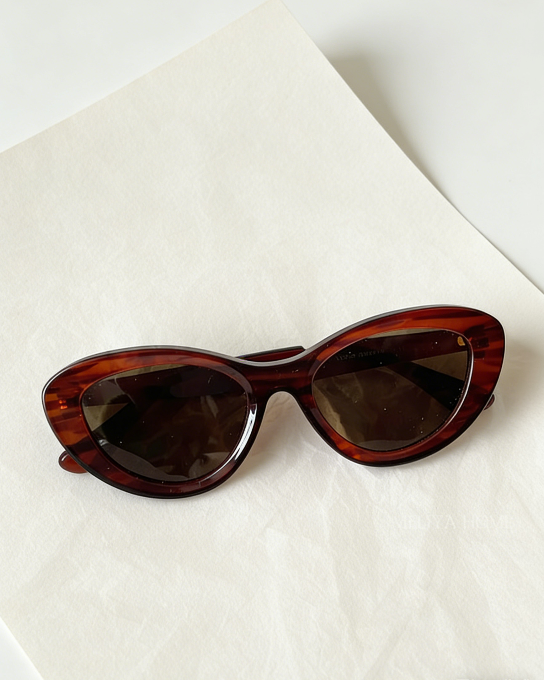 Bold black cat-eye sunglasses with thick frames, polarized lenses with UV protection, retro aesthetic eyewear for women. Brown wood grain pattern cat-eye sunglasses with tea-tinted polarized lenses and UV protection, vintage organic style eyewear.