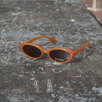 Make a unique statement with these playful oval sunglasses from By Charley. The retro unisex design in a warm pumpkin color features polarized lenses for all-day comfort.