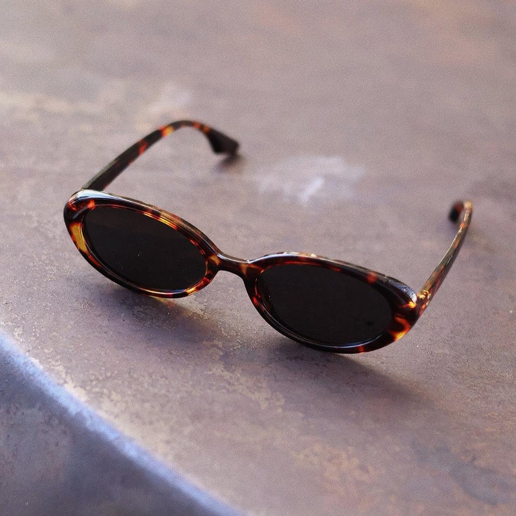 Playful and retro unisex oval sunglasses by By Charley, featuring a distinctive tortoiseshell frame and polarized lenses that offer 100% UV protection and glare reduction for a unique, fashion-forward look.